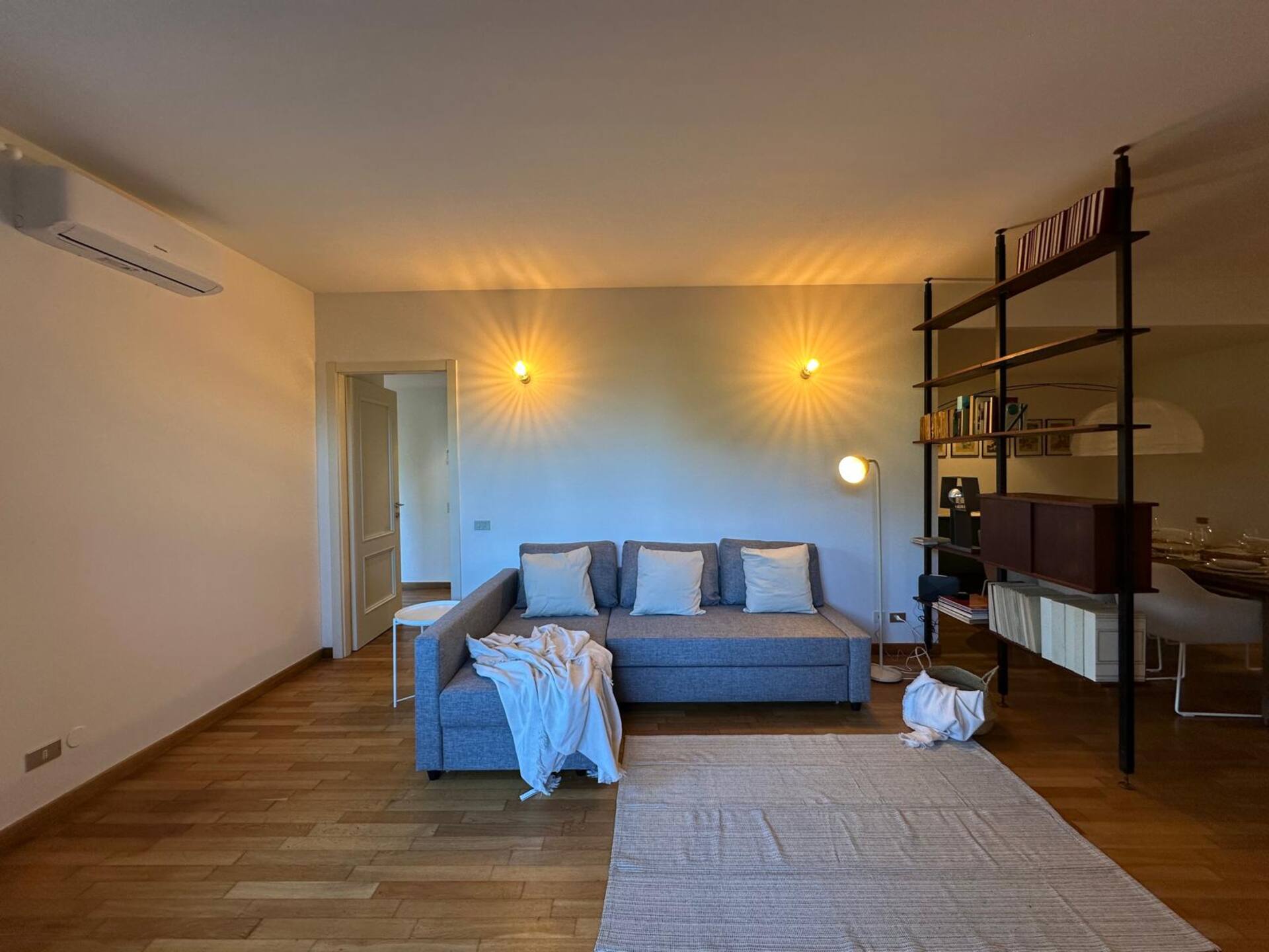 Ruime woonkamer met designerbank, dramatische wandlampen en industrieel wandrek