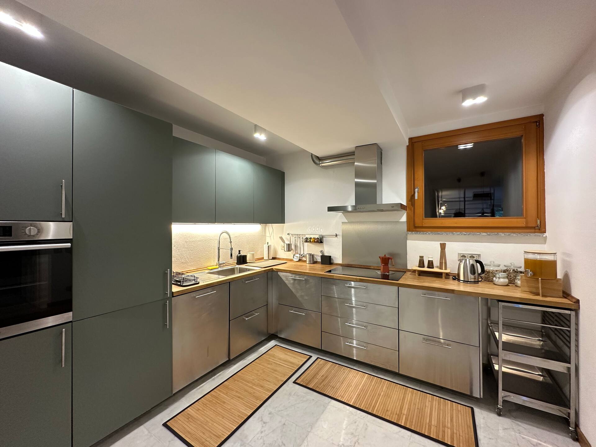 Moderne chef-keuken met saliekleurige kasten, houten werkbladen en ingebouwde apparatuur